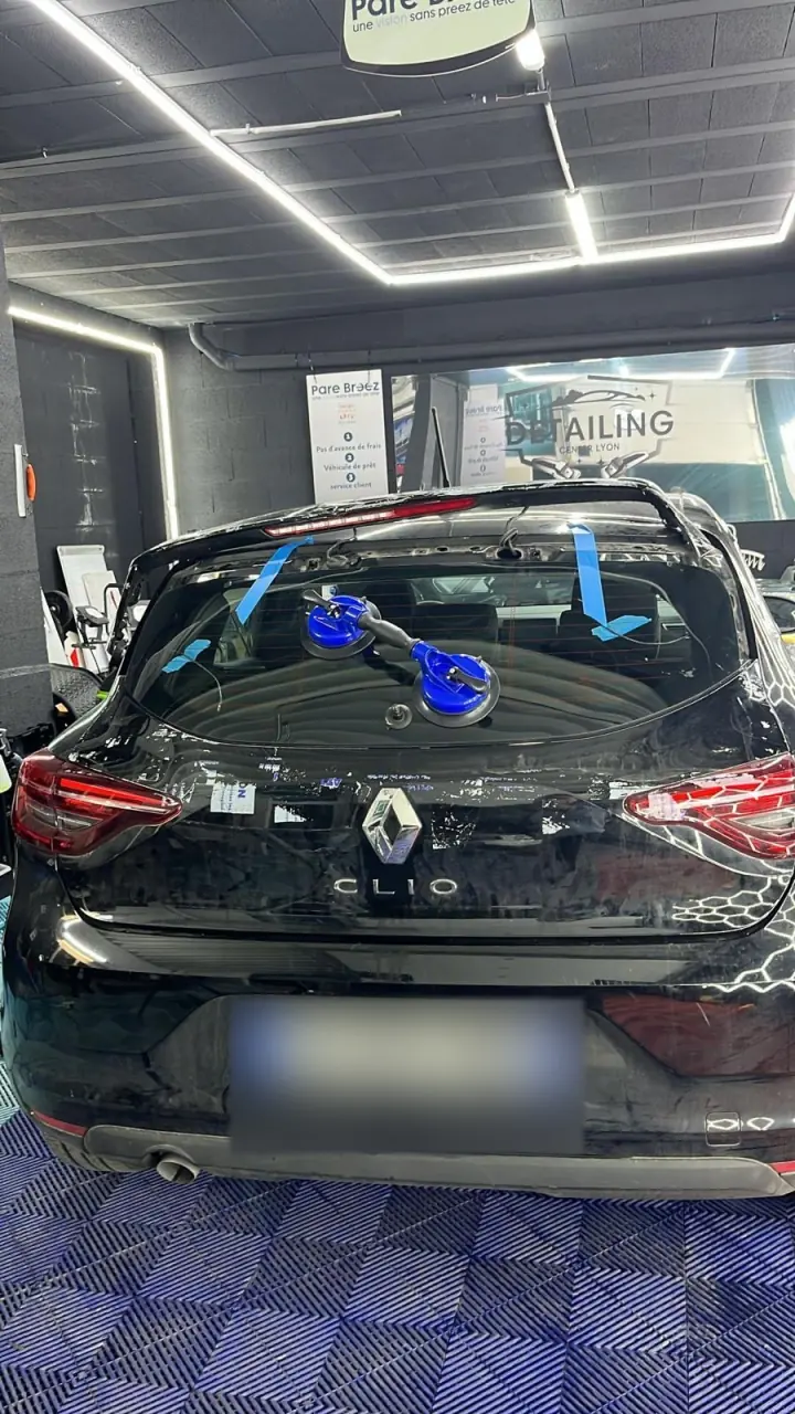 Lunette arrière neuve maintenue par des ventouses pendant le collage