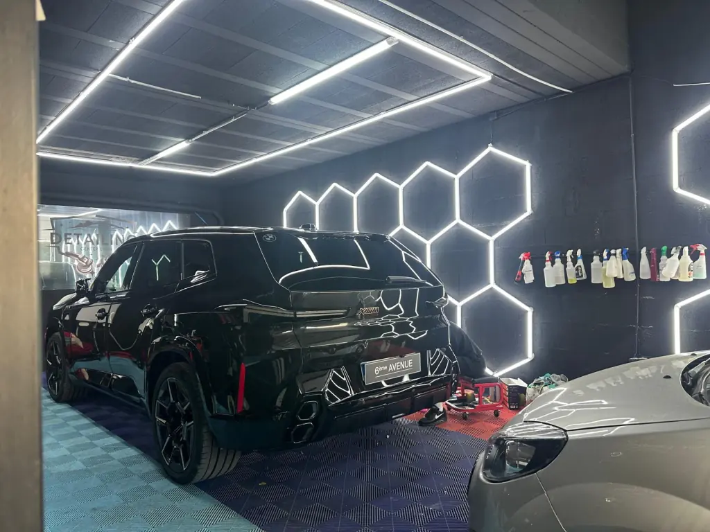 SUV noir lustré, reflets des éclairages de l’atelier sur la carrosserie