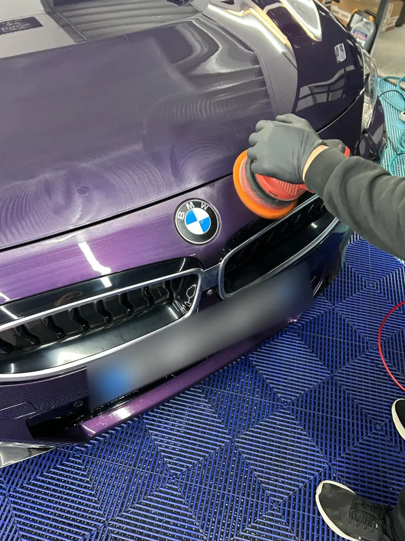 Polissage du capot d’une voiture violette à la polisseuse